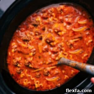 A bowl of Crockpot Lasagna Soup topped with a generous dollop of creamy cheese and fresh basil, ready to be enjoyed.