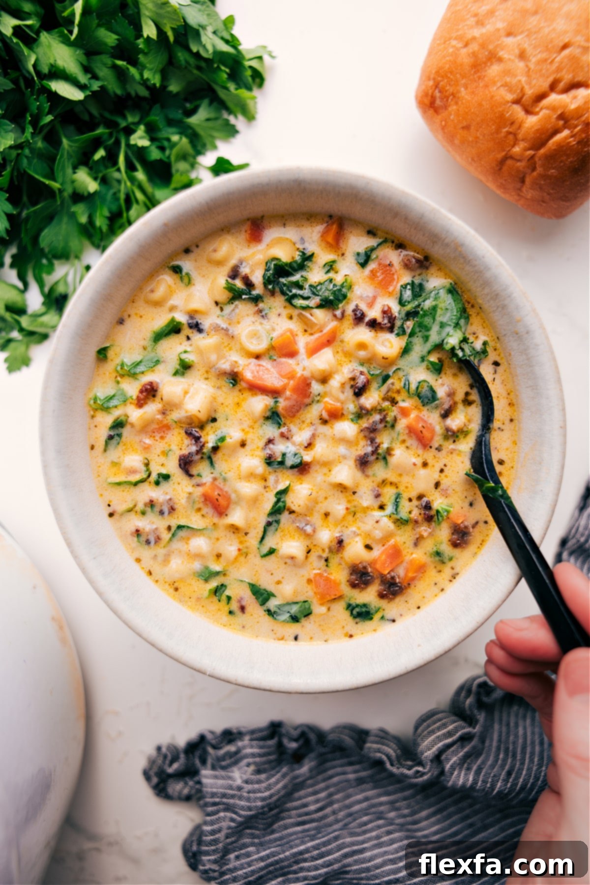The Ultimate Comfort Food: Creamy Parmesan Italian Sausage Soup A bowl of hot Creamy Parmesan Italian Sausage Soup served with a side of crusty bread, ready to be enjoyed as the ultimate comfort food.