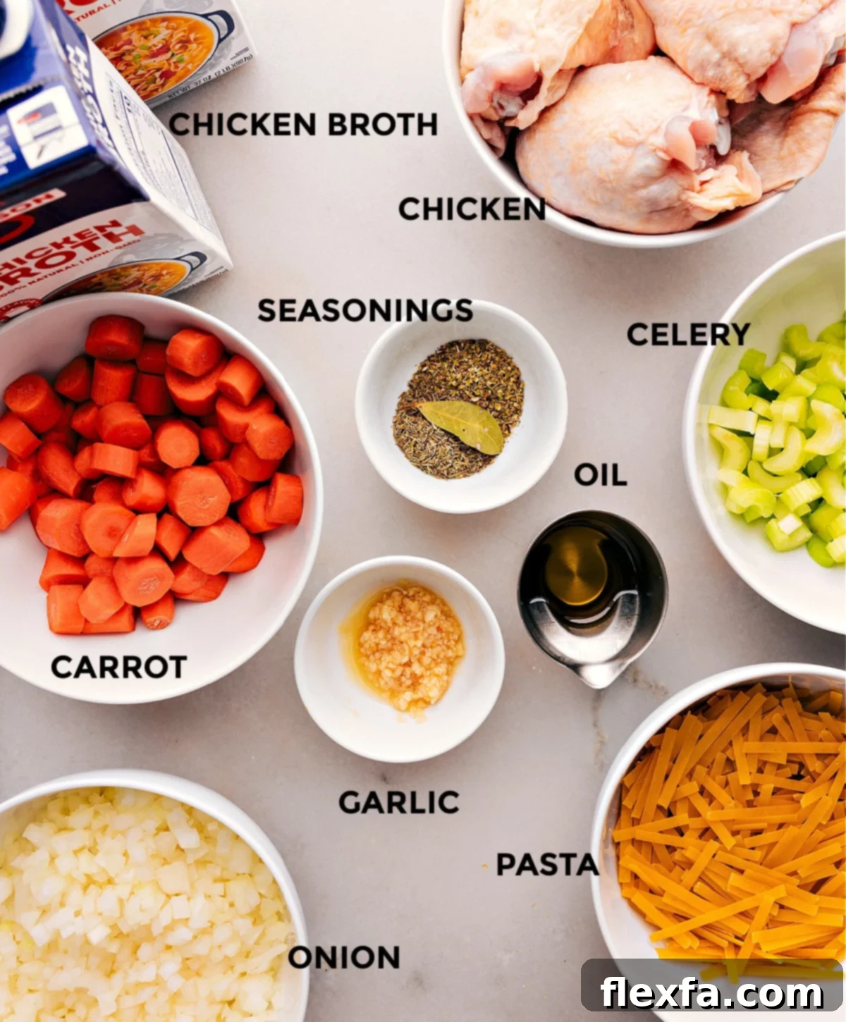 All the fresh ingredients for chicken noodle soup, including chicken thighs, vegetables, and herbs, arranged on a wooden board.
