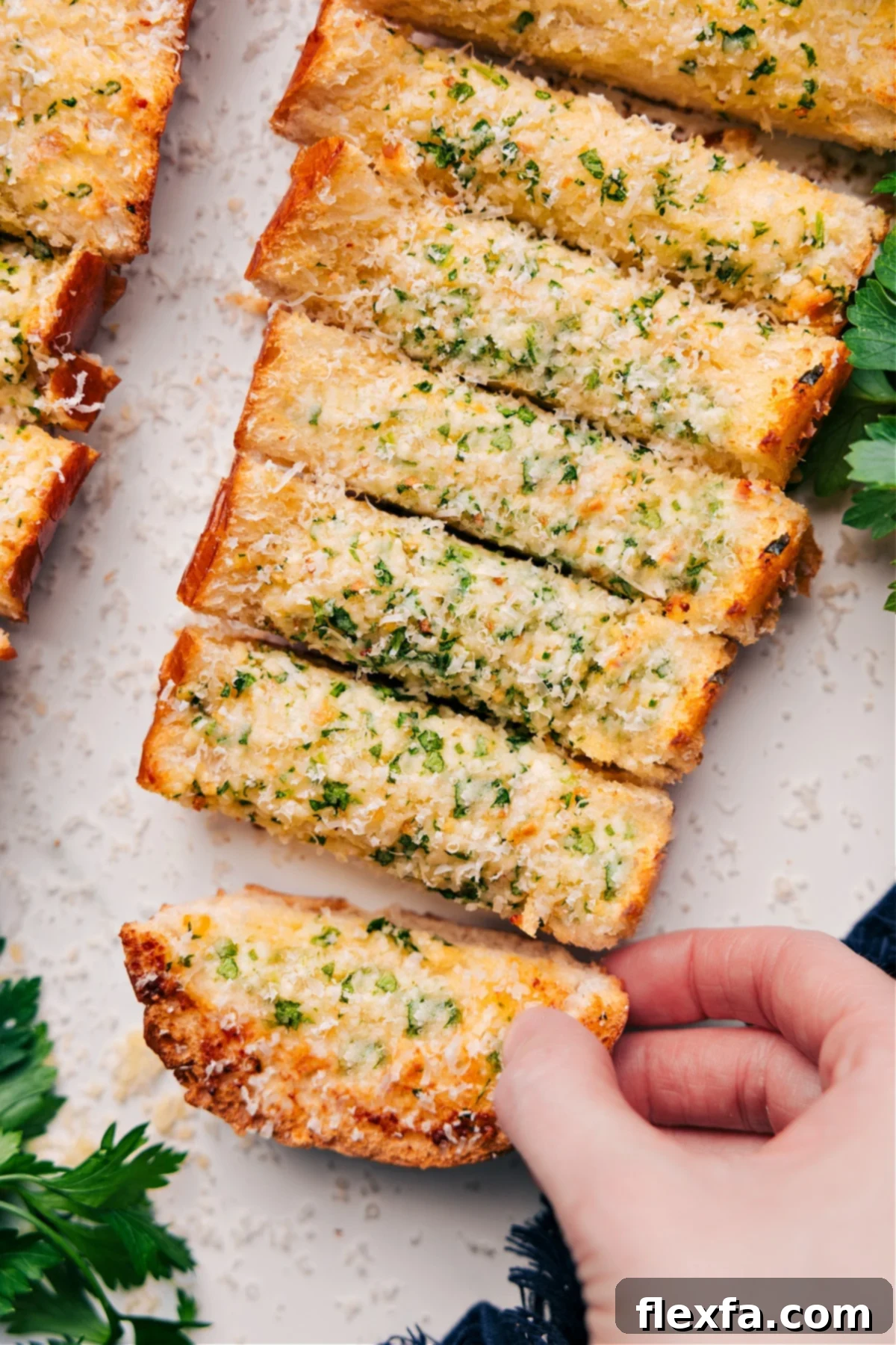 Garlic Bread Recipe cut into perfect slices, garnished with fresh Parmesan cheese and parsley, ready to be served alongside a delicious meal.
