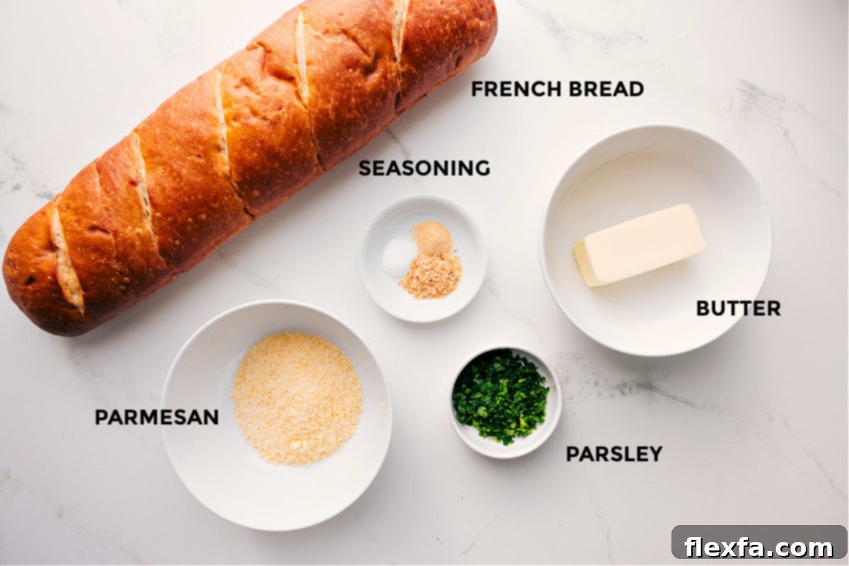 All the essential ingredients for this Easy Garlic Bread Recipe laid out: fresh French bread, grated Parmesan cheese, butter, granulated garlic, garlic powder, salt, and fresh parsley.