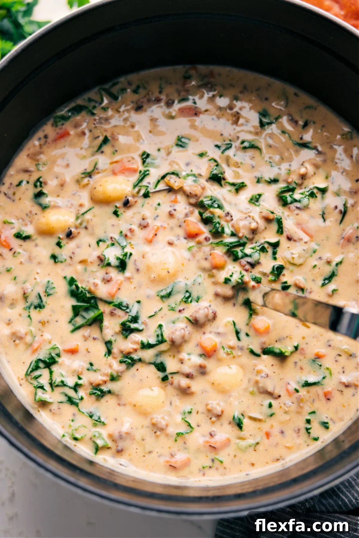 A vibrant bowl of Creamy Sausage Gnocchi Soup, garnished with fresh thyme, invitingly served on a rustic wooden surface. The steam rises gently, hinting at its warmth and comfort.