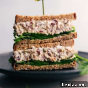 A delicious turkey salad sandwich, sliced in half, overflowing with creamy turkey salad and fresh lettuce, invitingly presented.