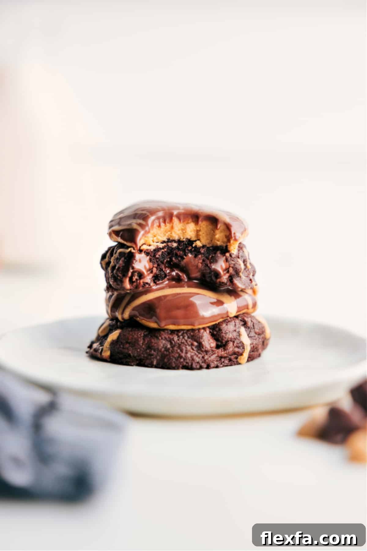 Stacked Buckeye Brownie Cookies with a bite taken out of the top one, showcasing the fudgy brownie base, creamy peanut butter center, and smooth chocolate topping.