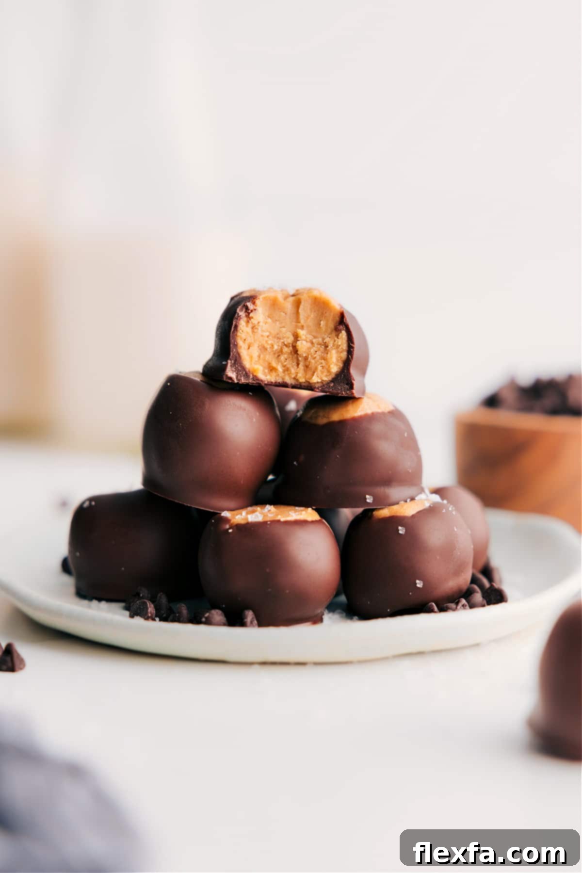 Buckeye Candy Recipe stacked all together on a plate ready to be enjoyed. Irresistible chocolate-dipped peanut butter balls with the signature exposed peanut butter 'eye'.