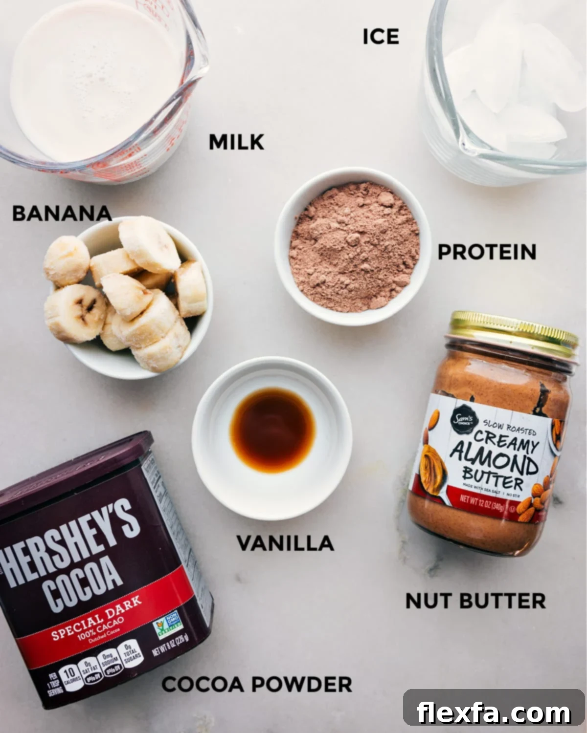All the ingredients including milk, ice, cocoa powder, nut butter, vanilla, and protein powder prepped out for easy assembly.