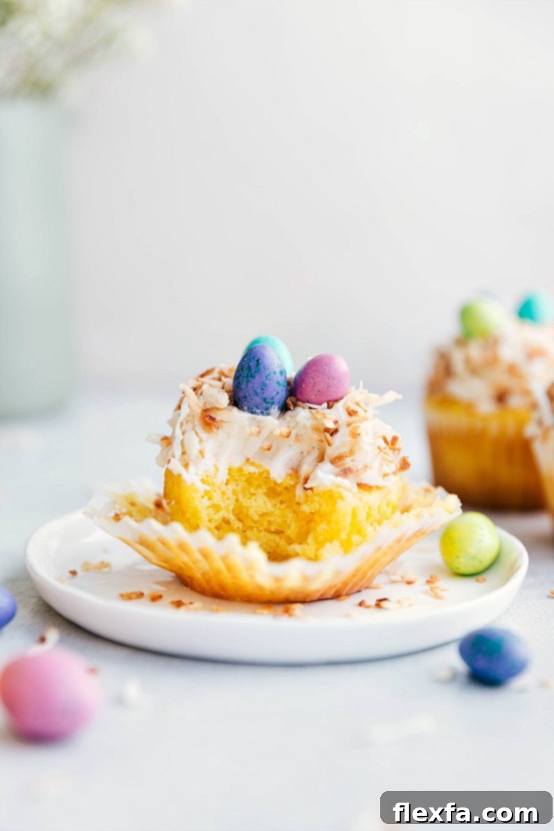 Bite taken out of a cupcake with other Easter cupcakes in the background, showcasing the moist yellow cake and creamy frosting.