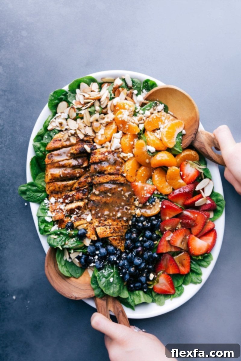 Elegant Chicken Spinach Salad Presentation: Freshly Dressed with Fruit and Nut Toppings Chicken spinach salad on a large platter, elegantly dressed and garnished with fresh fruit and nuts.