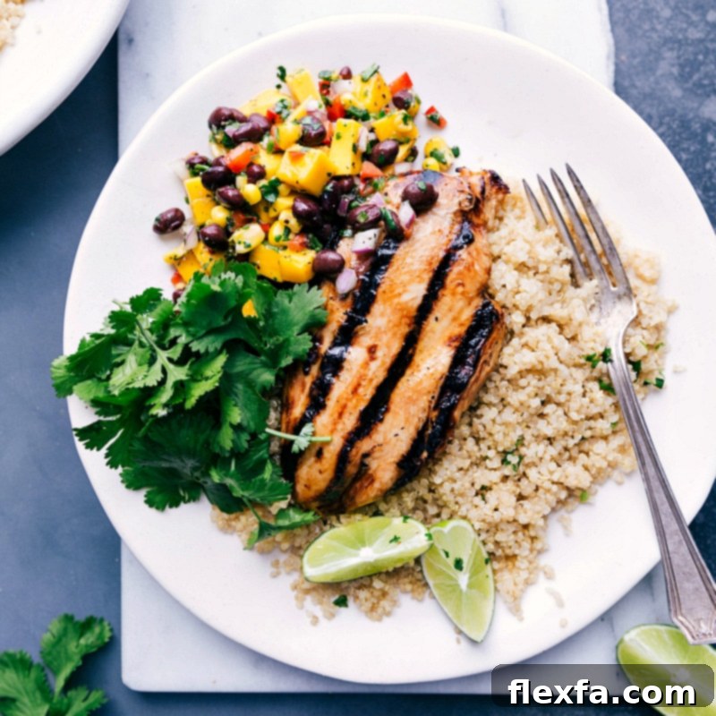 A delightful chicken quinoa bowl with mango salsa, rice, and fresh cilantro, perfectly plated and ready to be enjoyed.