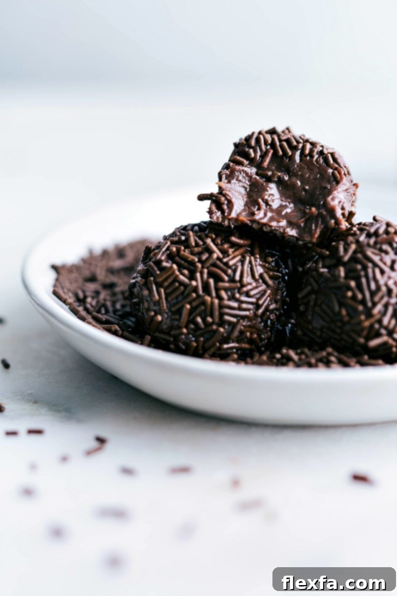Brigadeiros with a bite out of one of them, showing the fudgy interior.