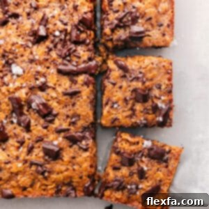 Overhead view of soft-baked oatmeal breakfast bars cut into squares, with a few pieces on a plate.