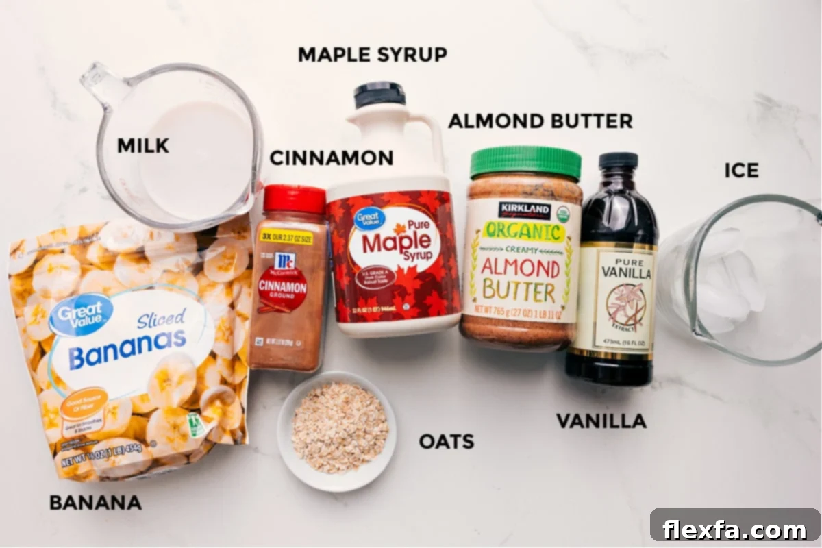 All the ingredients for the oatmeal smoothie recipe, including bananas, milk, oats, cinnamon, maple syrup, almond butter, vanilla, and ice, neatly arranged.
