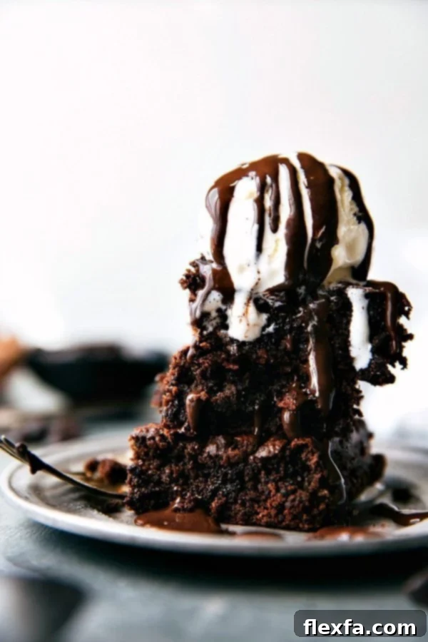 Indulge in these super fudgy, double-chocolate applesauce brownies – free from oil, butter, and flour! A truly healthy and quick dessert recipe via Chelseasmessyapron. #dessert #healthy #quick #easy #best #nobeans #betterforyou #applesauce #brownies Fudgy Applesauce Brownies served with a scoop of vanilla ice cream and drizzled with chocolate syrup, ready to be enjoyed.