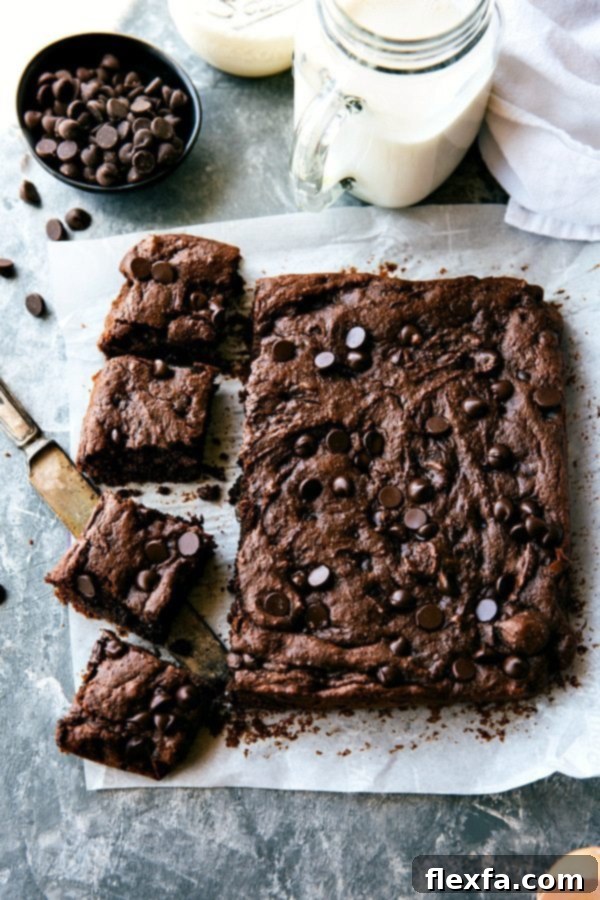 These double-chocolate, super fudgy applesauce brownies are incredibly easy to make, featuring no oil, no butter, and no flour! A wholesome dessert recipe by Chelseasmessyapron. #dessert #healthy #quick #easy #best #nobeans #betterforyou #applesauce #brownies A close-up shot of baked Applesauce Brownies being cut into neat squares, revealing their rich, fudgy texture.