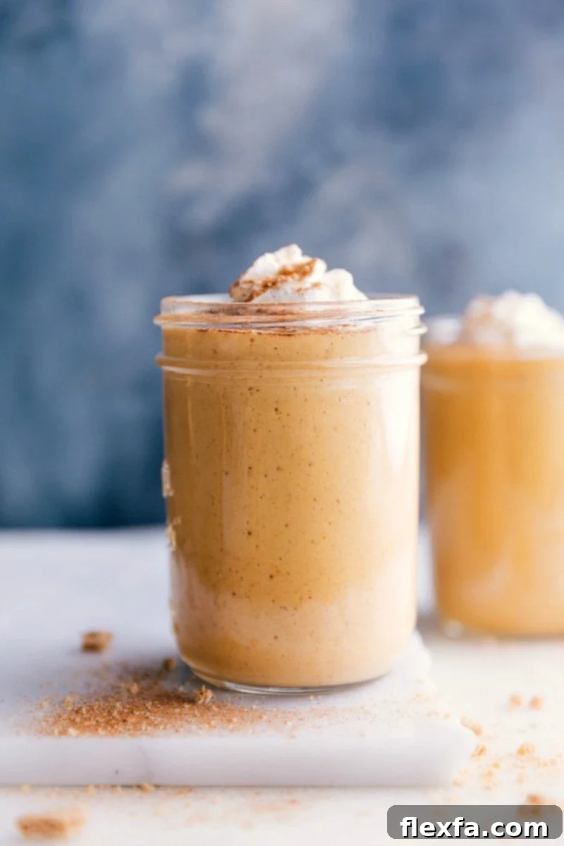 A cup filled with a creamy pumpkin protein shake, topped with a swirl of whipped cream and a sprinkle of cinnamon, ready to be enjoyed.