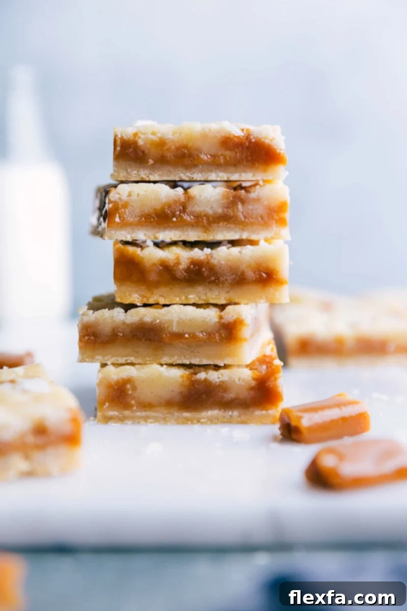 A stack of freshly baked caramel cookie bars, sliced to display a soft and gooey caramel-filled interior, surrounded by a crisp golden crust, rich in flavor. Garnished with a light dusting of sea salt.