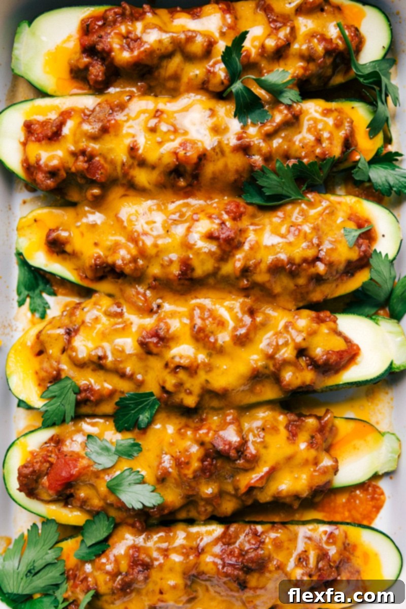 Zucchini boats fresh out of the oven, topped with melted cheese and fresh parsley, showcasing the finished recipe ready to be served.