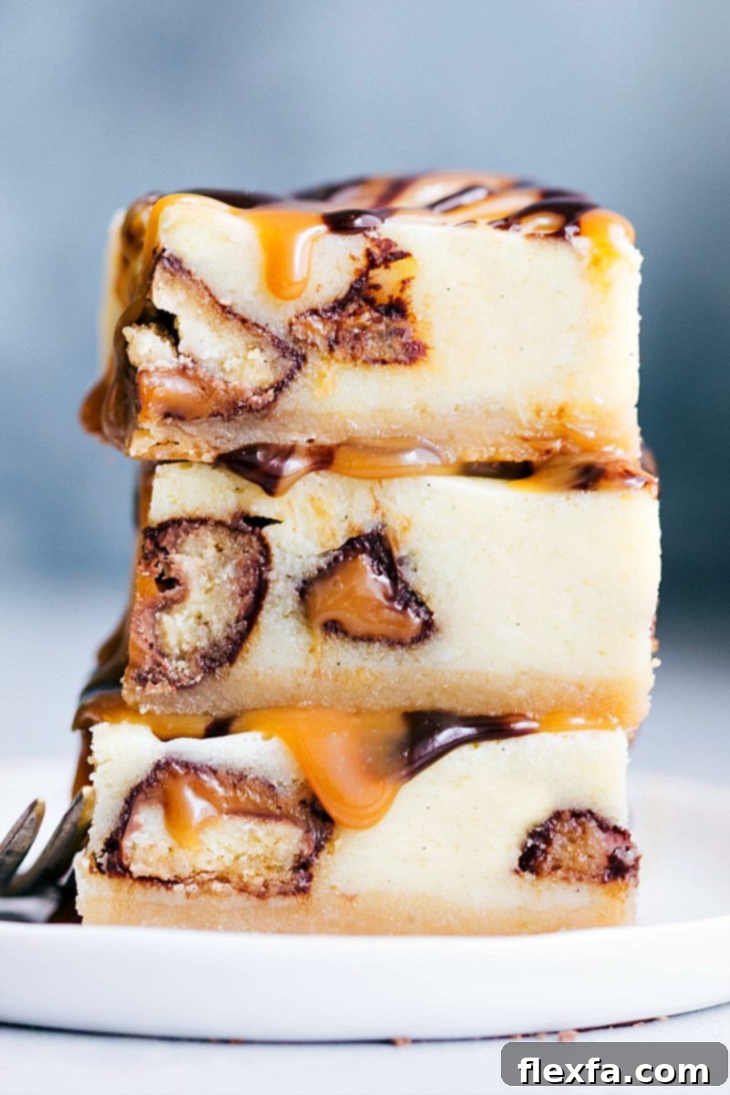 Stack of three Twix Cheesecake Bars showcasing the layers of crust, cheesecake, Twix, caramel, and chocolate ganache