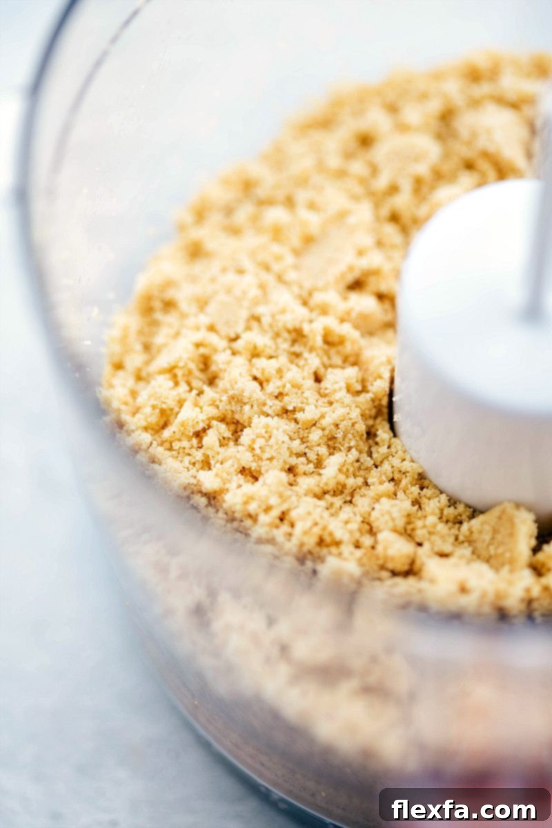 Crushed shortbread cookies mixed with butter and sugar, ready for pressing into the pan for the cheesecake crust
