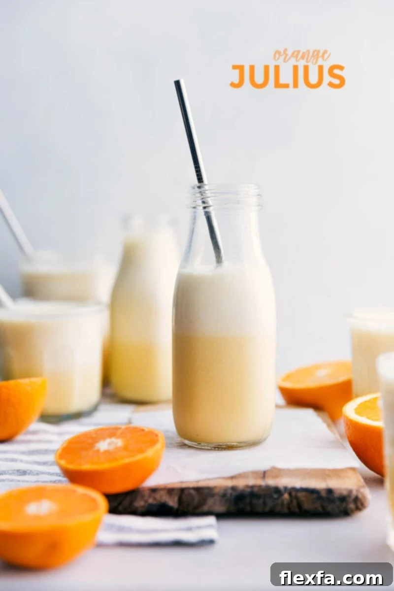 A copycat orange Julius recipe, perfectly blended and ready to enjoy. A couple cups of Orange Julius with fresh orange slices and a straw on the side.