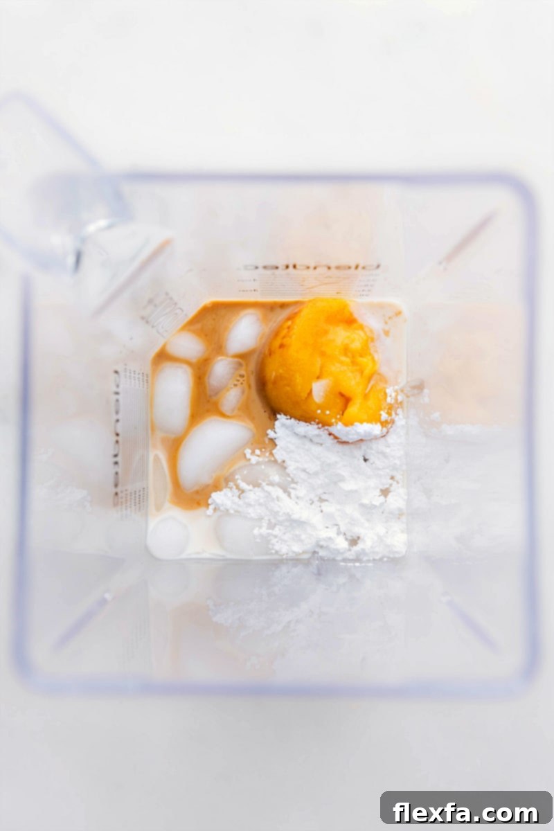 How to make Orange Julius: Ingredients going into the blender. Ingredients for Orange Julius being added to a blender.