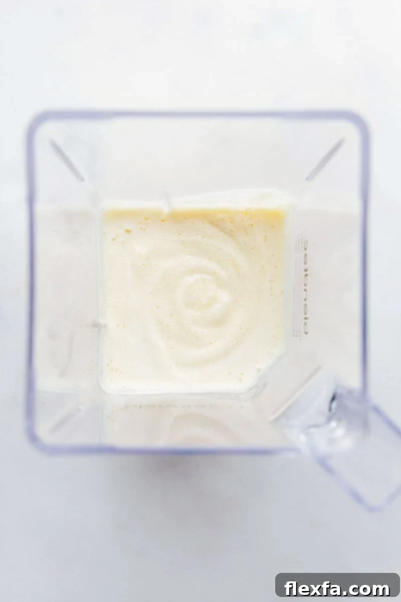 Orange Julius recipe showing the frothy, creamy drink after blending. Blended Orange Julius still in the blender, showing its frothy texture.