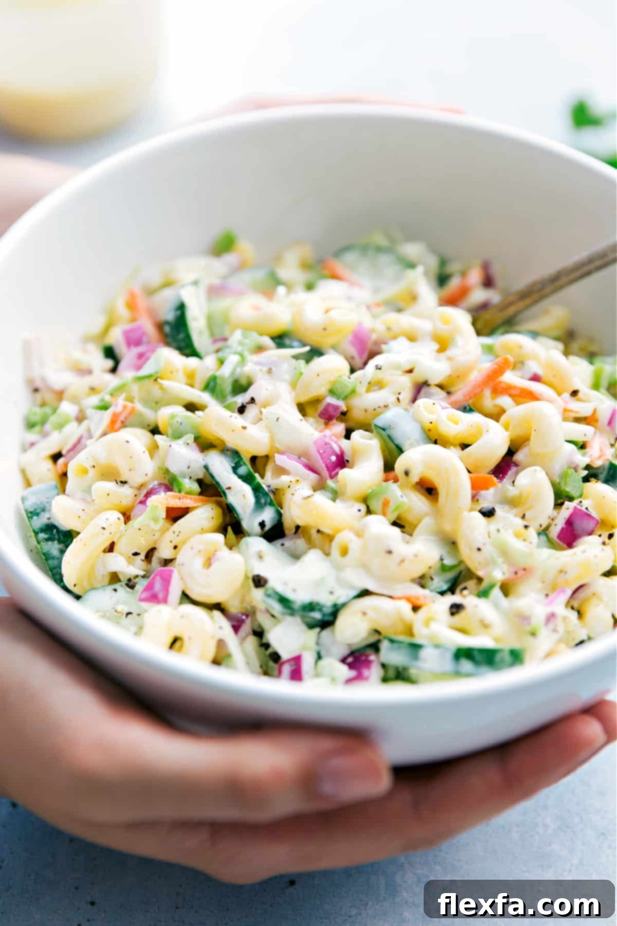 Someone holding a bowl full of the best Macaroni Coleslaw Salad, ready to be served.
