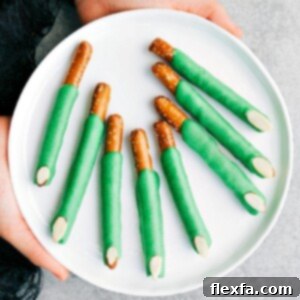 Green Witch Finger Pretzels with almond 'nails' on a baking sheet.