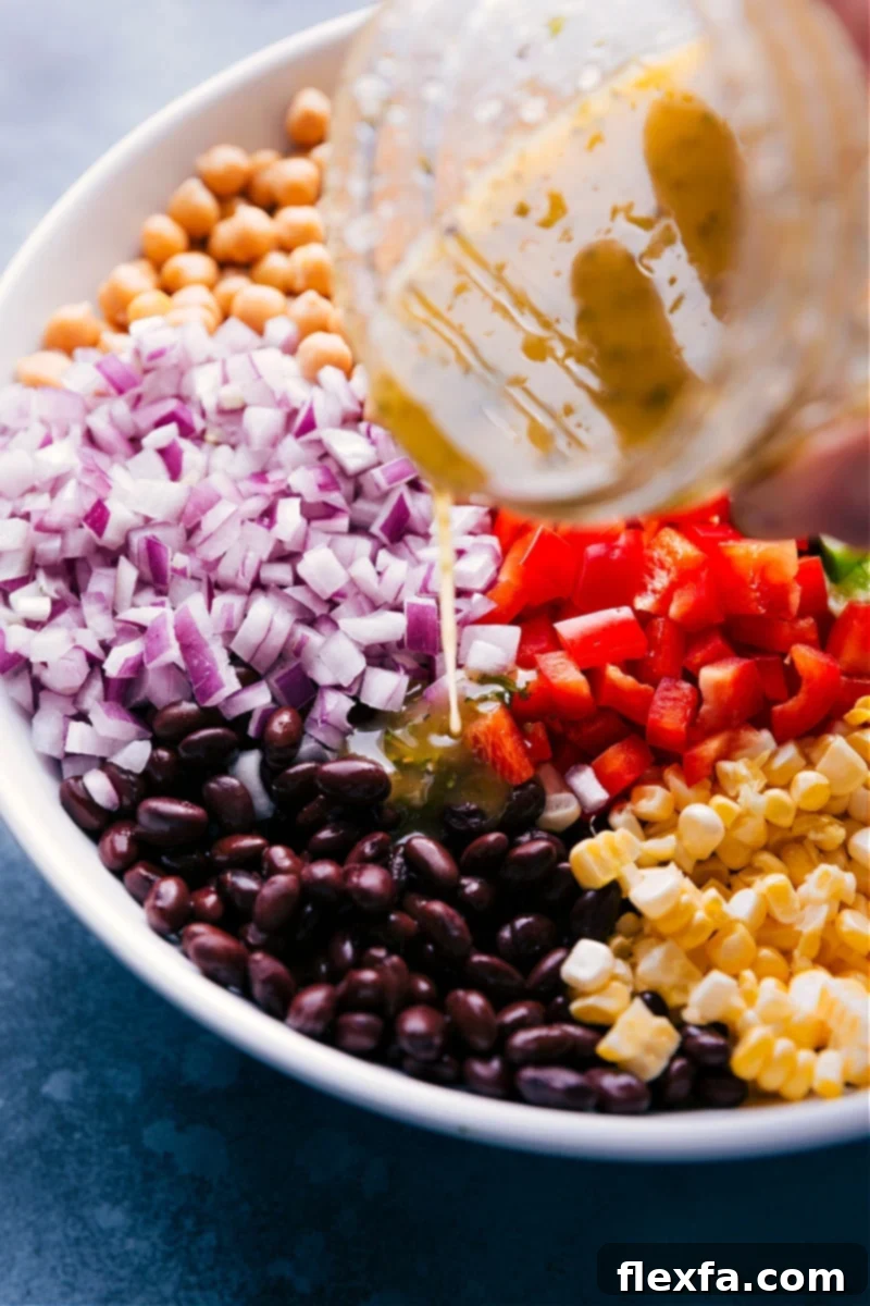 Image of the rich Italian dressing being generously poured over the colorful Garbanzo Bean Salad, ready to be tossed.