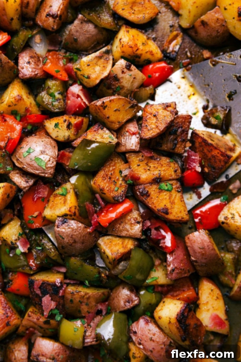 Close-up of freshly baked one-pan breakfast potatoes with bell peppers and onions, topped with crispy bacon.