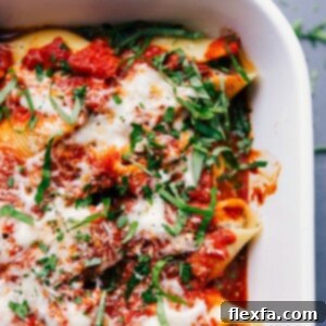 A pan of stuffed shells with sausage, topped with melted cheese and a basil chiffonade, presenting a warm and delicious meal suitable for any occasion.