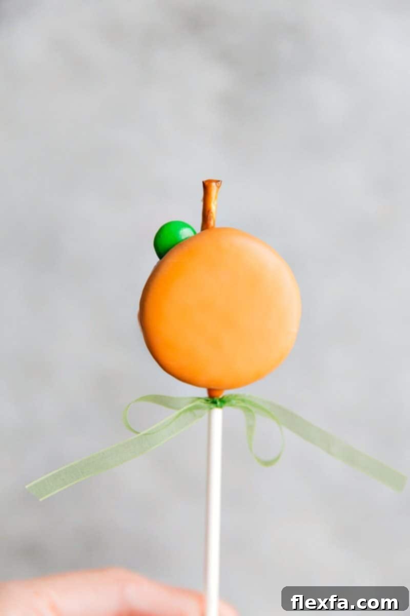 Spooktacular Oreo Pop Treats 8 A vibrant Pumpkin Oreo Pop, adorned with a pretzel stem and green M&M leaf, ready for fall and Halloween celebrations.