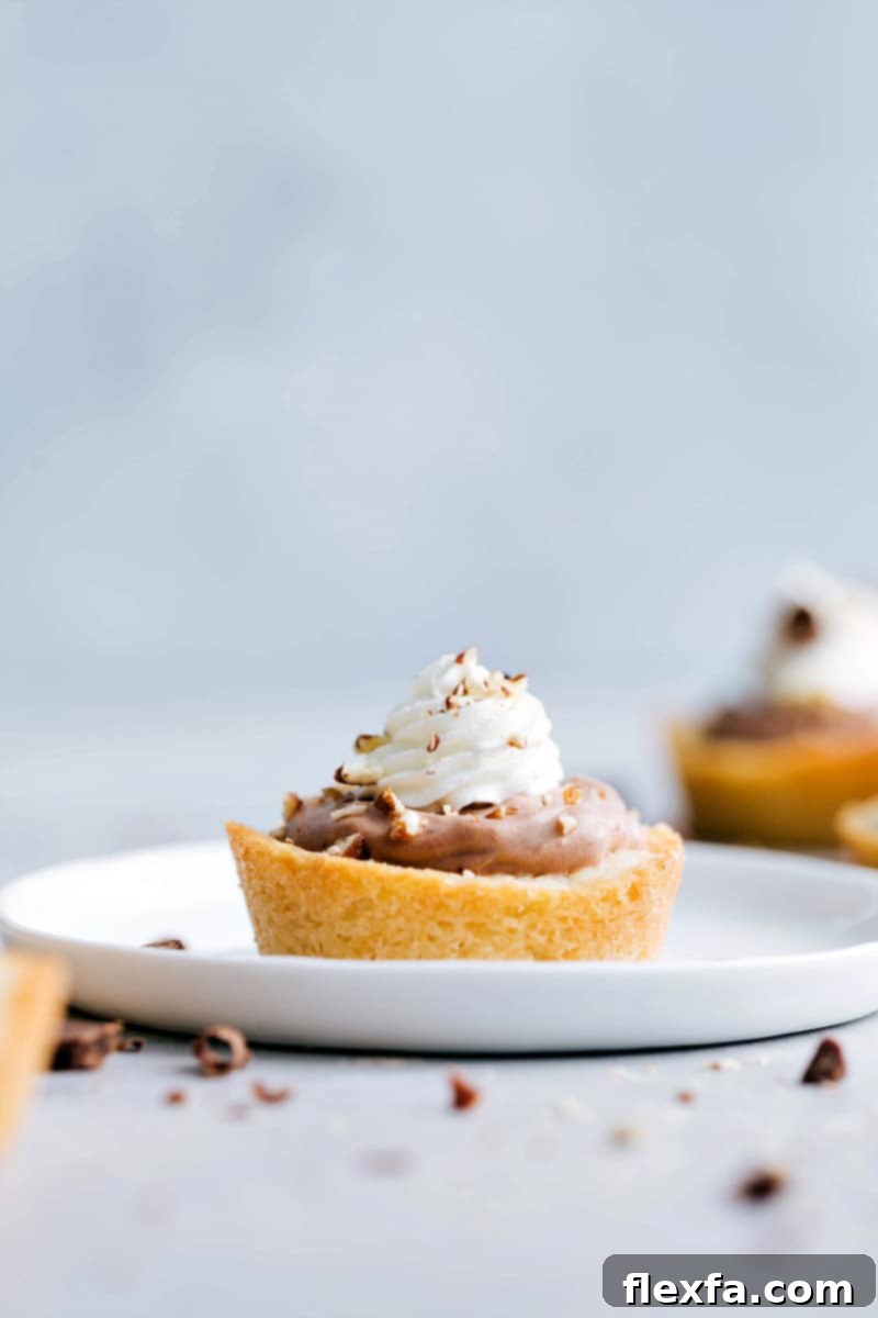 Close-up of three Sugar Cookie Turtle Pudding Bites, showcasing the perfect layers of golden cookie, gooey caramel, rich chocolate pudding, and fluffy whipped cream with pecan topping.