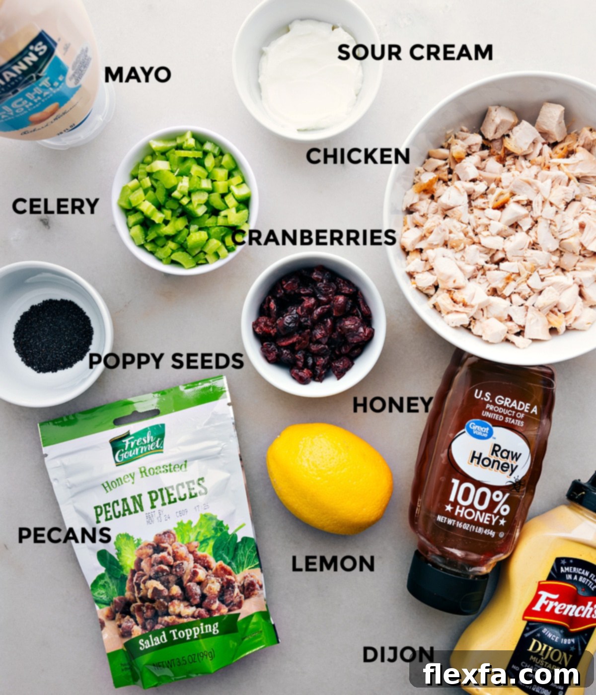 Ingredients In Chicken Salad Recipe All the vibrant ingredients for the chicken salad recipe including shredded chicken, creamy mayo, sour cream, crisp celery, sweet cranberries, crunchy poppy seeds, fresh lemon, tangy Dijon mustard, toasted pecans, and a drizzle of honey, all prepped out for easy assembly.