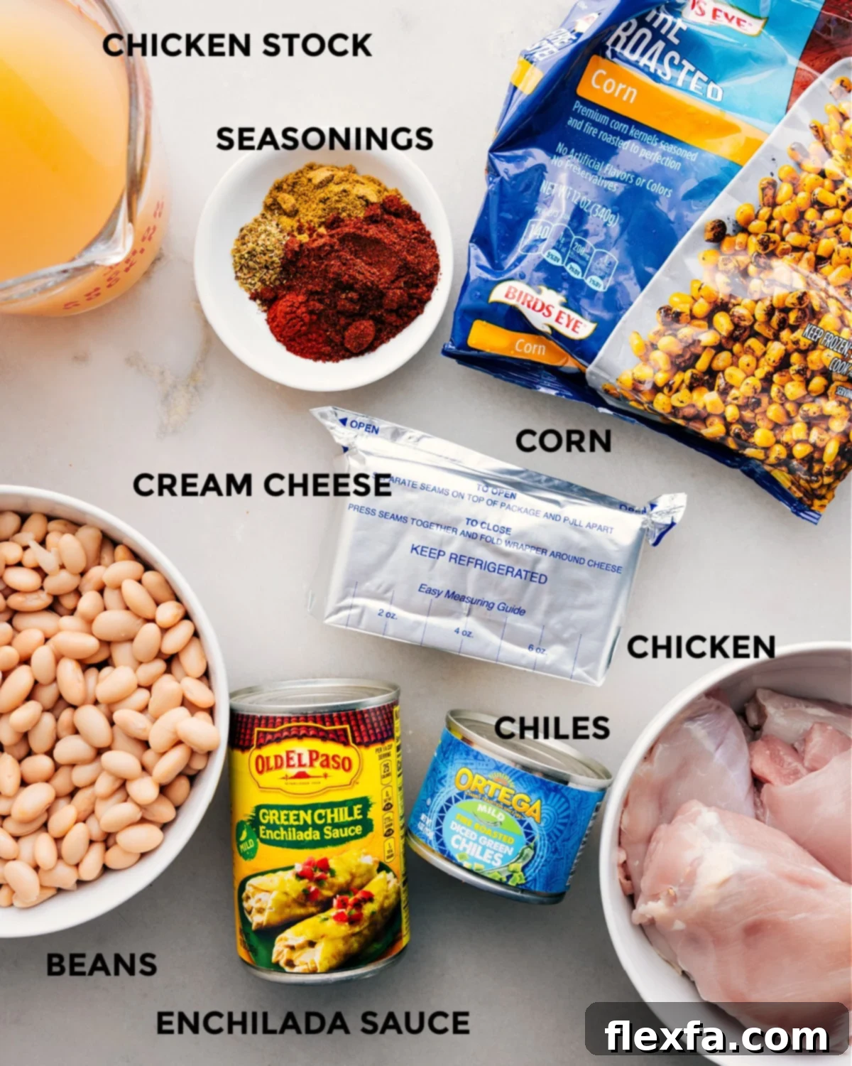 All the essential ingredients for Crockpot White Chicken Chili laid out, including chicken, green enchilada sauce, chicken stock, cream cheese, white beans, corn, diced green chiles, and a blend of spices.
