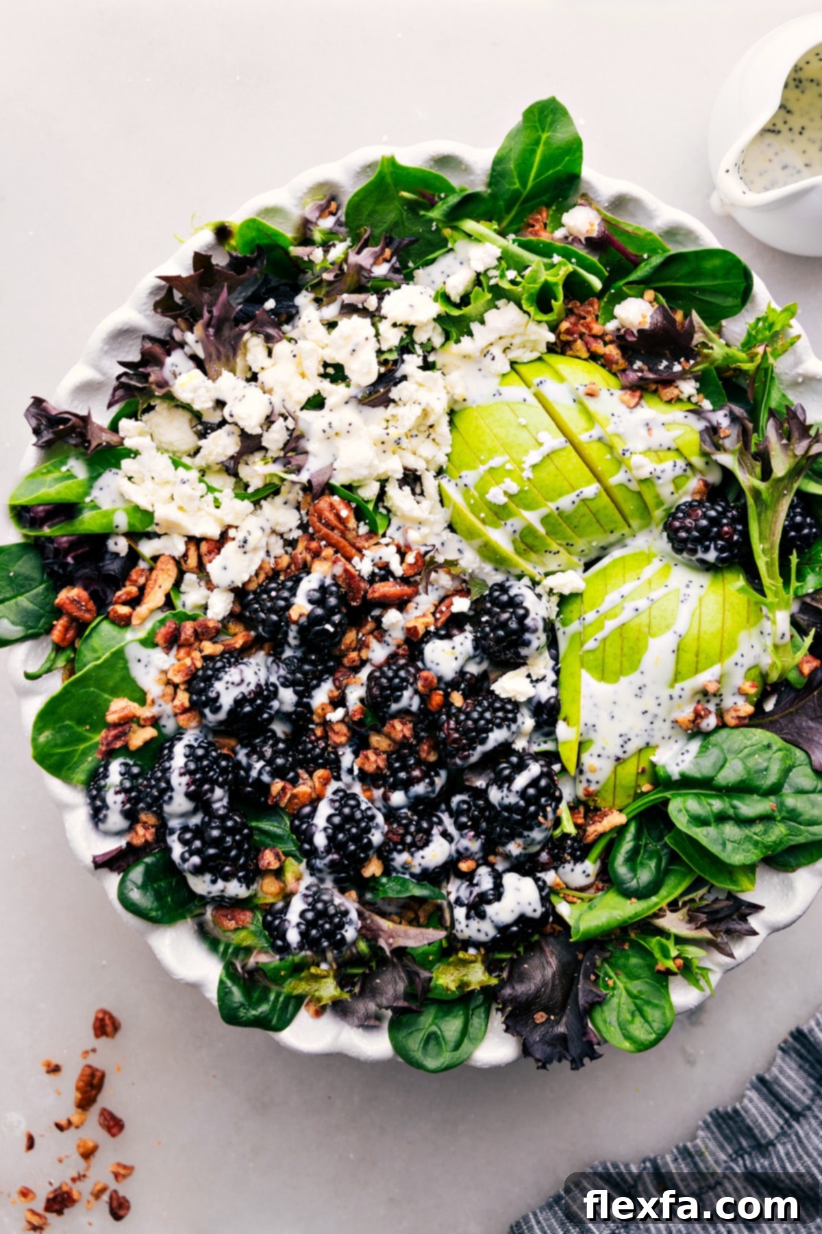 A beautifully arranged Blackberry Salad with poppyseed dressing in a large white bowl, garnished with fresh mint.