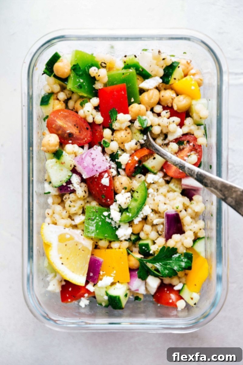 Greek couscous salad dressing and tossed together with a fork in it ready to be enjoyed.