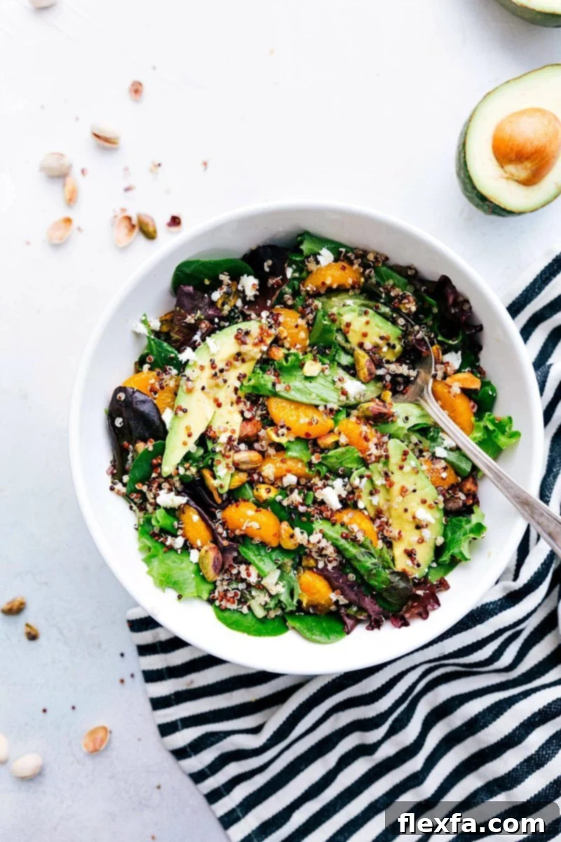 Overhead image of a vibrant Citrus Quinoa Salad in a large serving bowl, beautifully showcasing fresh clementine segments, green mixed lettuce, fluffy golden quinoa, and chopped pistachios, ready to be enjoyed.