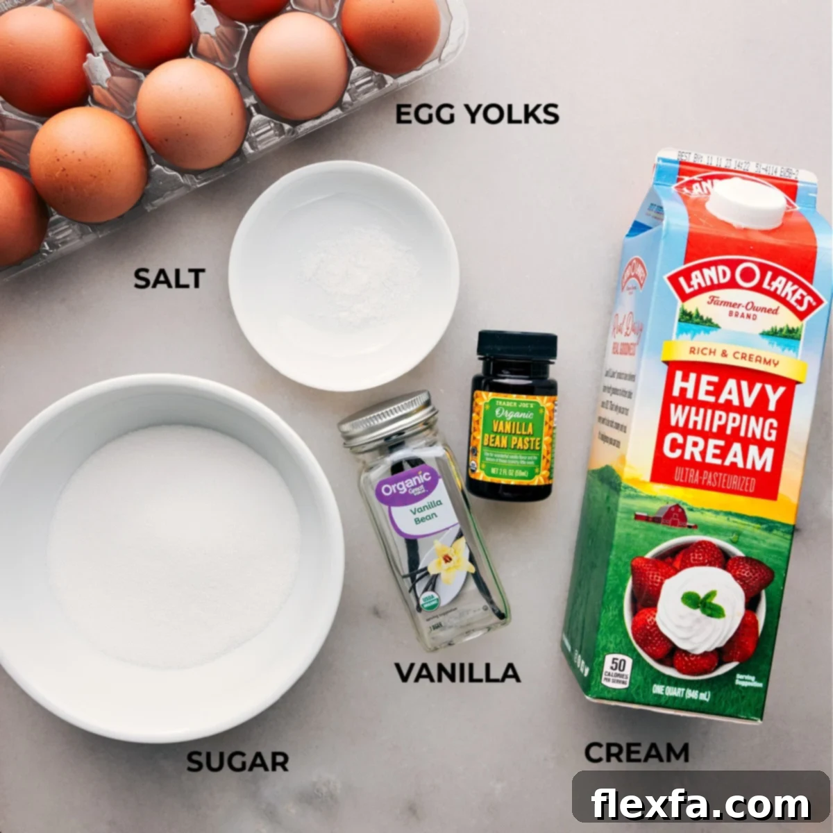 A beautiful flat lay of all the essential ingredients laid out for making the perfect Crème Brûlée recipe, including fresh eggs, granulated sugar, a fragrant vanilla bean, rich heavy cream, and a pinch of salt.