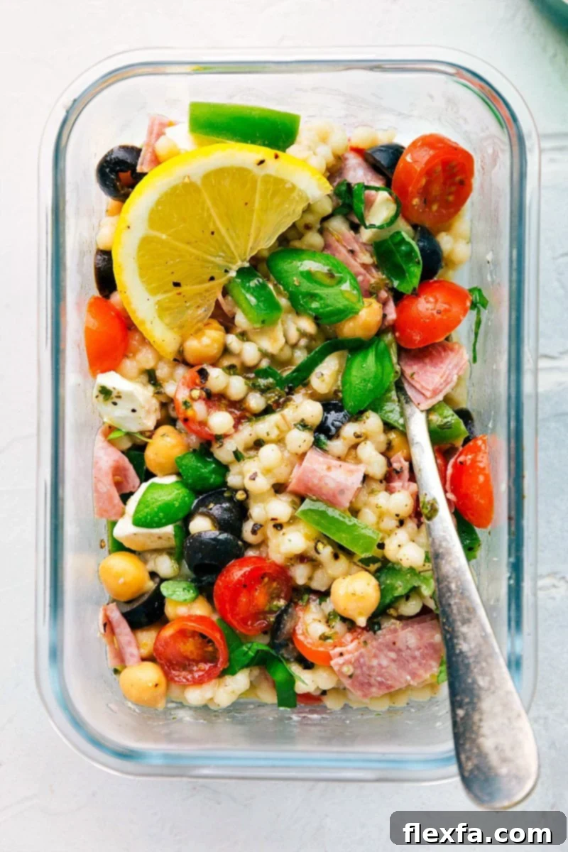 A close-up of the vibrant Italian Couscous Salad ingredients, including fresh basil, cherry tomatoes, and mozzarella.