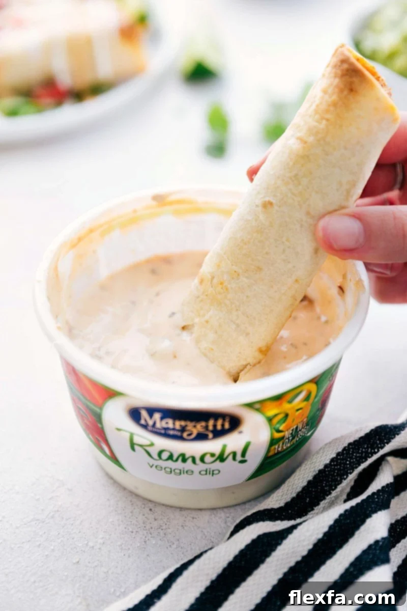 A close-up shot of the creamy, cheesy chicken filling being spread evenly onto a small tortilla, ready to be rolled into a taquito.