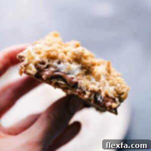 A close-up of a s'mores cookie bar, showcasing its irresistibly gooey marshmallow and melted chocolate center, ready to be enjoyed.