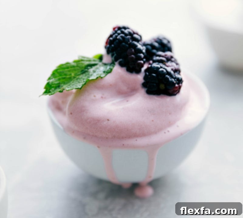 Strawberry Frozen Yogurt served in a bowl with a generous topping of mixed fresh berries.