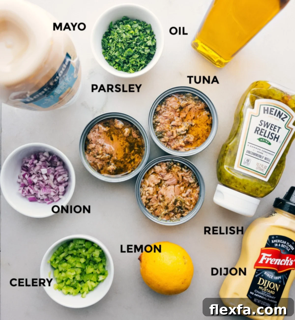 Ingredients Assembled All the essential ingredients for making the best tuna salad laid out on a clean surface: mayo, fresh parsley, olive oil, canned tuna, red onion, pickle relish, lemon, dijon mustard, and chopped celery.