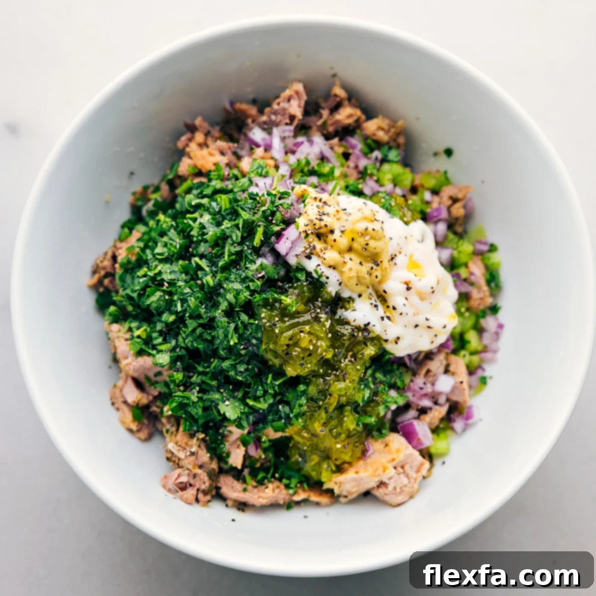 The Best Tuna Salad The absolute best tuna salad served in a elegant white bowl after it has been freshly prepared, garnished with a sprig of parsley.