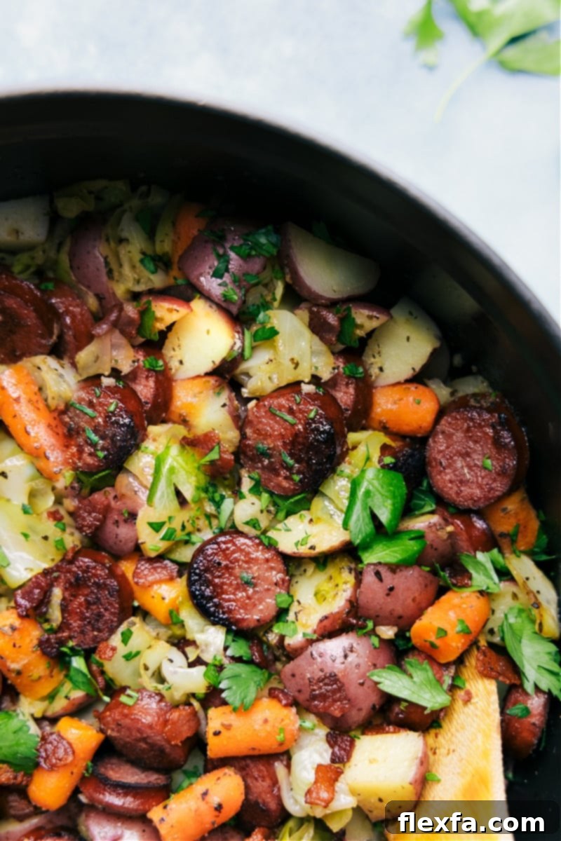 A spoonful of the one-pot cabbage, potatoes, and sausage dish being served from the pot.