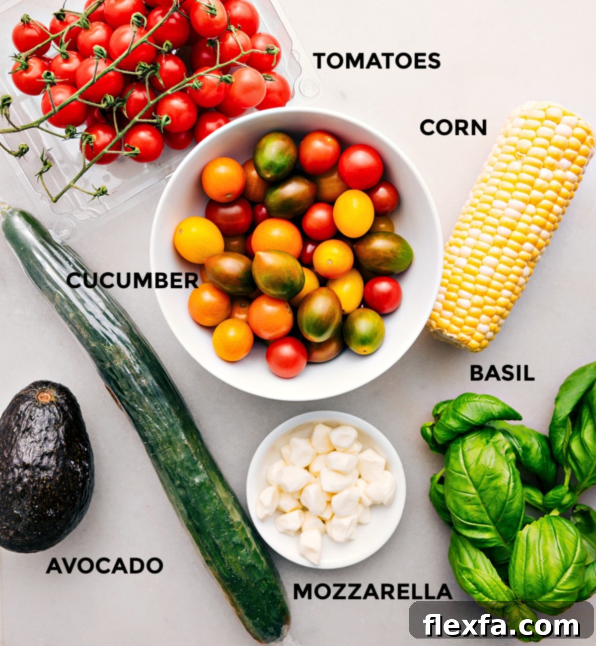 All the ingredients for this recipe are prepped for easy assembly, including the tomatoes, corn, cucumber, basil, mozzarella, and avocado.