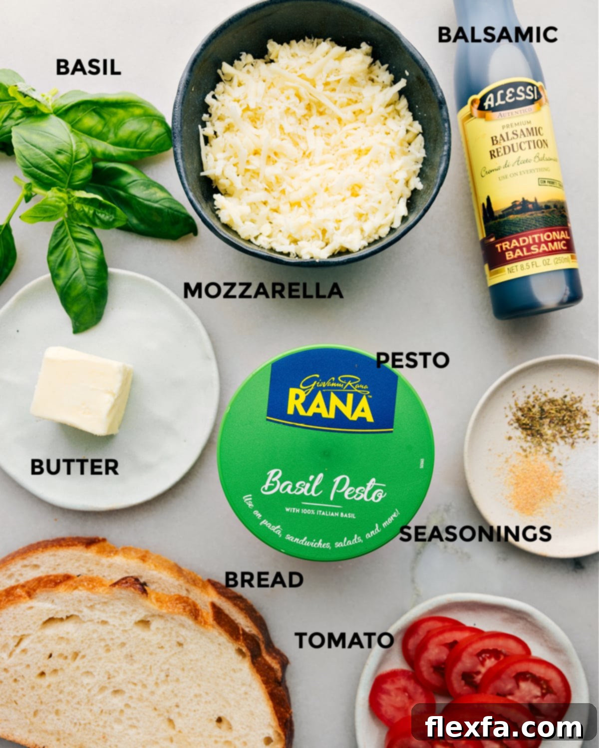 The vibrant ingredients for Caprese Grilled Cheese including fresh basil, balsamic reduction, mozzarella cheese, basil pesto, butter, seasonings, sliced Roma tomatoes, and thick-cut sourdough bread.