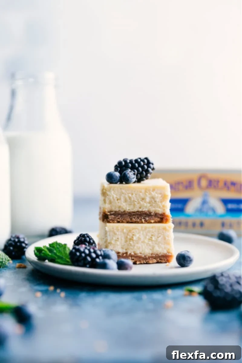 Smooth, creamy, and indulgent vanilla Cheesecake Bars with a thick, sweet graham cracker crust, perfect for topping with berries, caramel, or a simple berry sauce. Stacked image of creamy vanilla cheesecake bars with a thick graham cracker crust, garnished with fresh berries