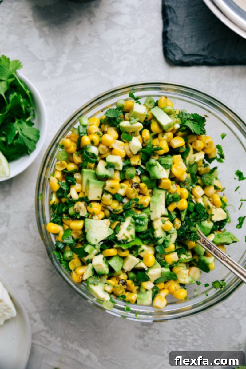 Hands preparing fresh ingredients like corn, avocado, and cilantro for taco toppings